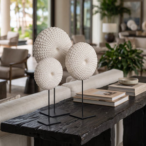 Heinimex Sea Urchin on Stand centerpiece, textured white stone finish with black metal stand, modern coastal luxury lifestyle photo in set