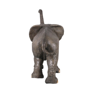Decorative statue of a walking baby elephant featuring textured grey skin, large flared ears, and a high raised trunk.