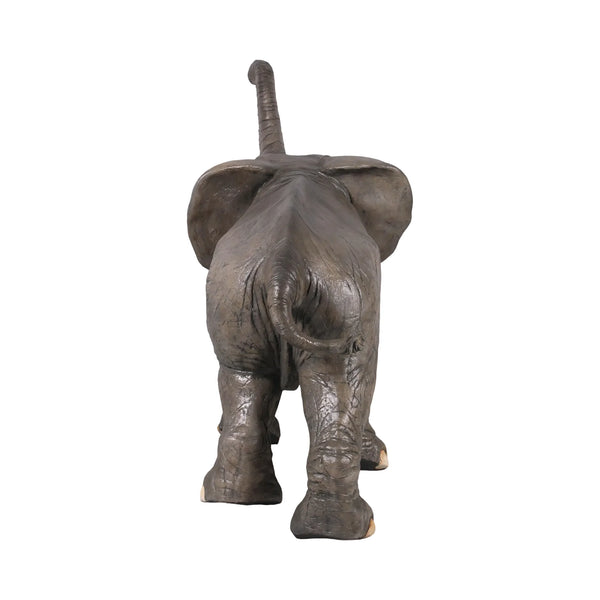 Decorative statue of a walking baby elephant featuring textured grey skin, large flared ears, and a high raised trunk.