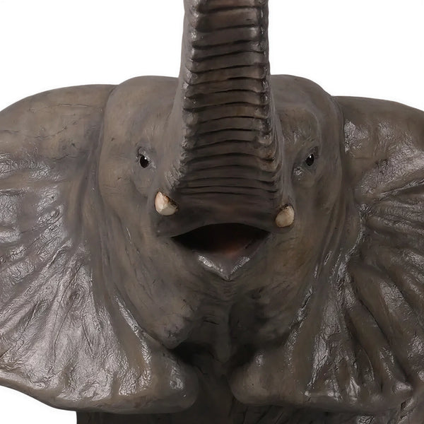 Decorative statue of a walking baby elephant featuring textured grey skin, large flared ears, and a high raised trunk.
