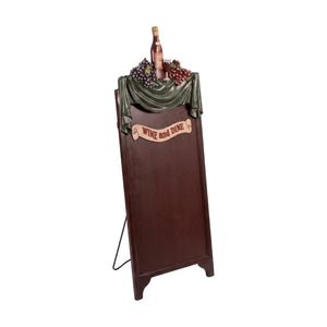 Decorative freestanding menu board featuring a dark writing surface topped with a sculpted wine bottle, grapes, and a Wine and Dine banner.