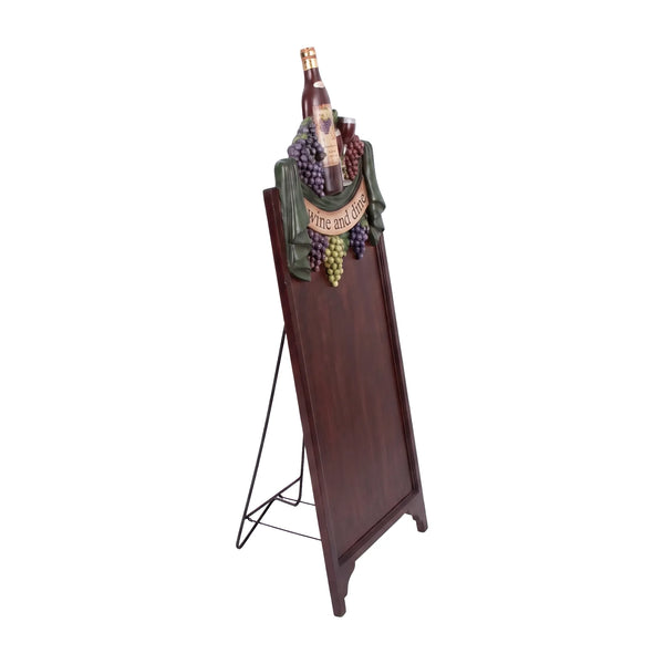 Decorative freestanding menu board featuring a dark writing surface topped with a sculpted wine bottle, grapes, and a Wine and Dine banner.