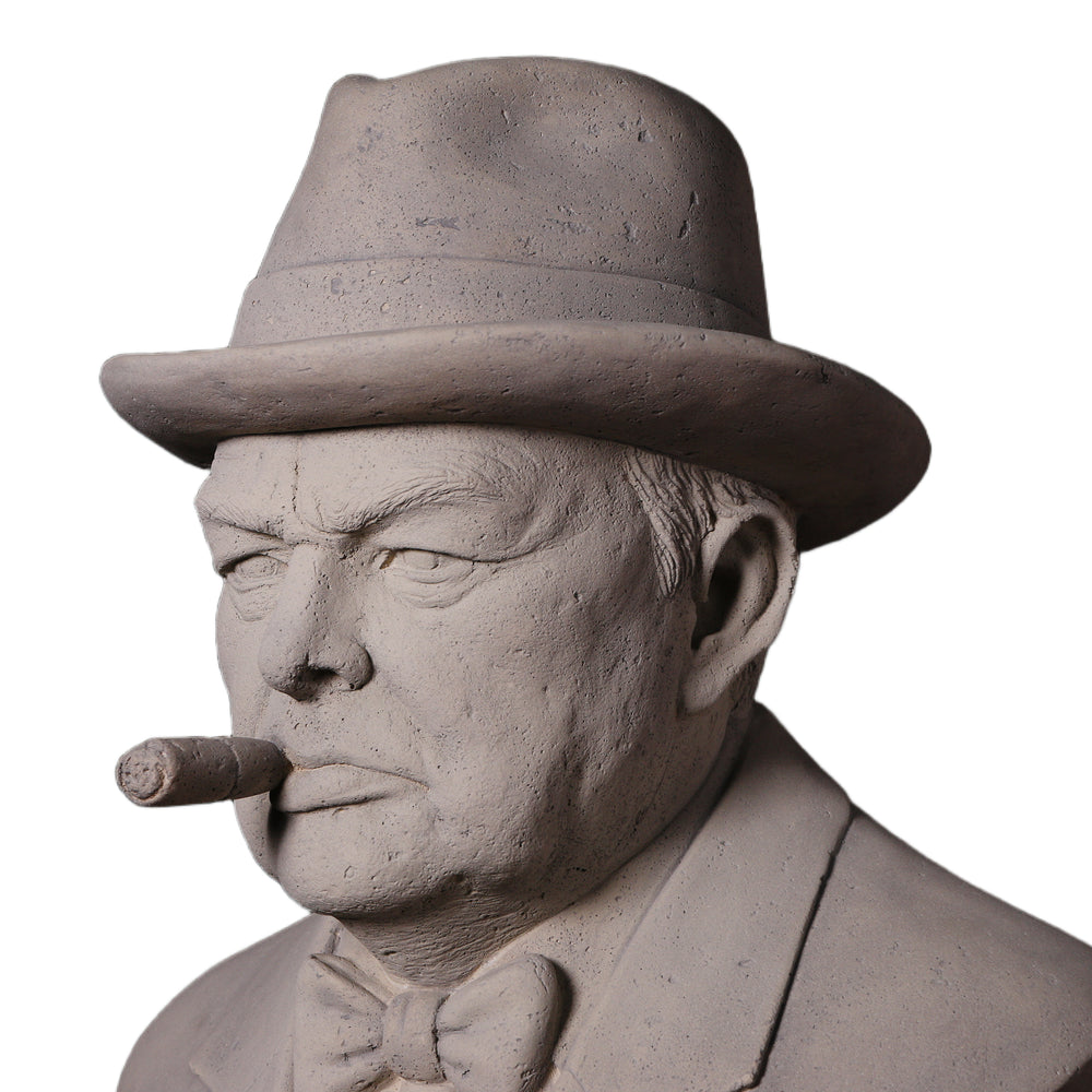 Decorative grey stone-like bust of Winston Churchill wearing a hat and bow tie, with a sculpted cigar in his mouth.