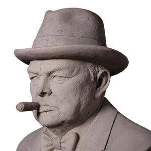Decorative grey stone-like bust of Winston Churchill wearing a hat and bow tie, with a sculpted cigar in his mouth.
