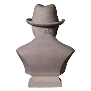 Decorative grey stone-like bust of Winston Churchill wearing a hat and bow tie, with a sculpted cigar in his mouth.