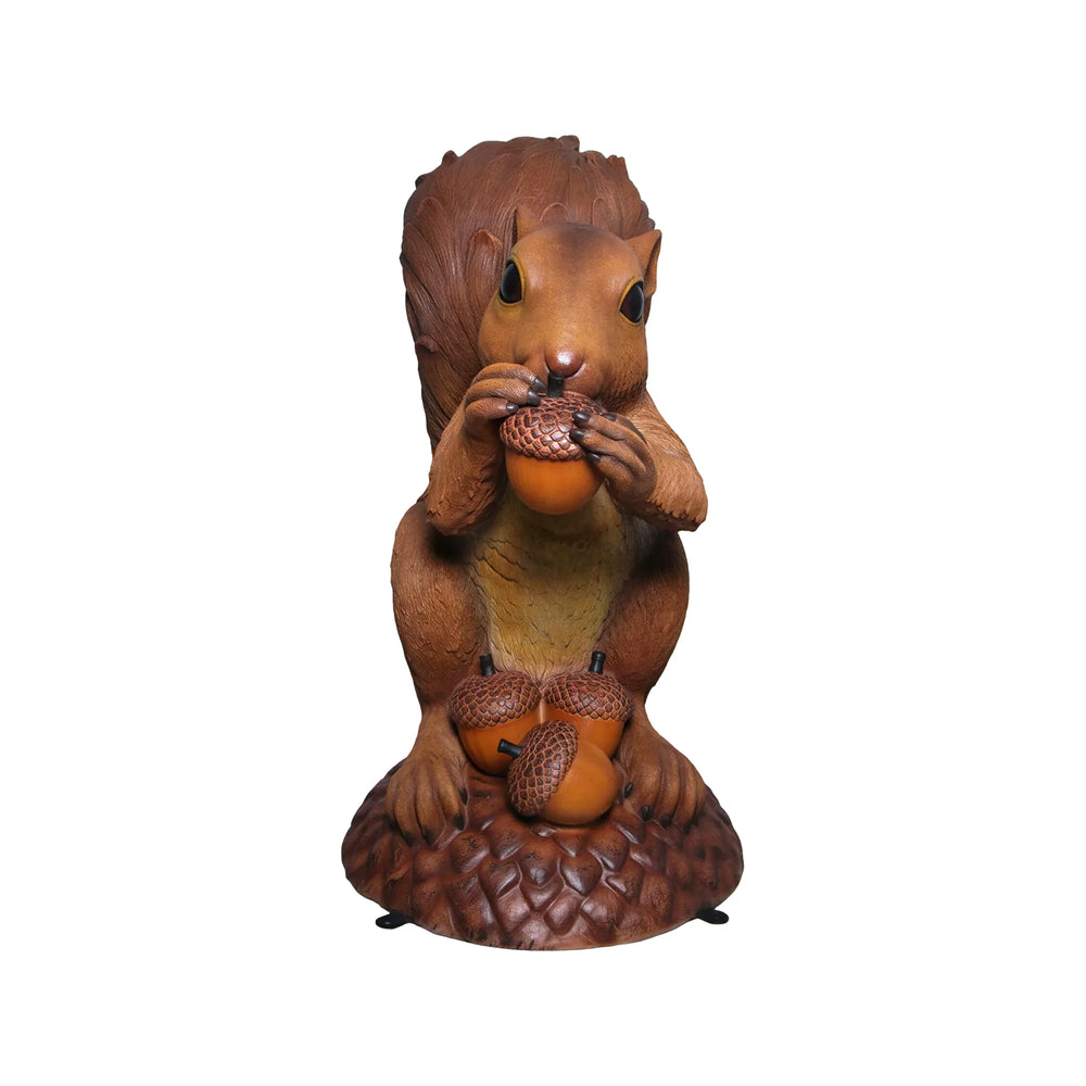 Decorative statue of a large brown squirrel holding an acorn, sitting upright on a textured base with additional acorns.