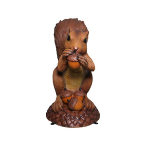 Decorative statue of a large brown squirrel holding an acorn, sitting upright on a textured base with additional acorns.