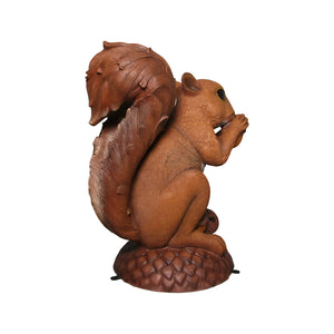 Decorative statue of a large brown squirrel holding an acorn, sitting upright on a textured base with additional acorns.