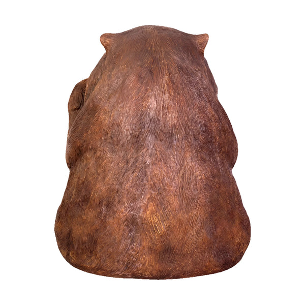 Decorative statue of a smiling wombat sitting upright with a brown finish and large textured foot pads.