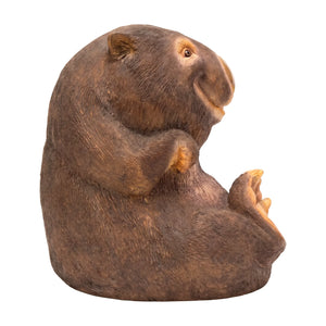 Decorative statue of a smiling wombat sitting upright with a brown finish and large textured foot pads.