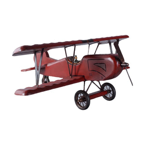 Decorative wooden biplane model featuring a dark red finish, spoked wheels, and a small pilot figure.