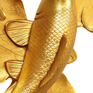 Decorative gold sculpture featuring two koi fish swimming among textured lily pads.