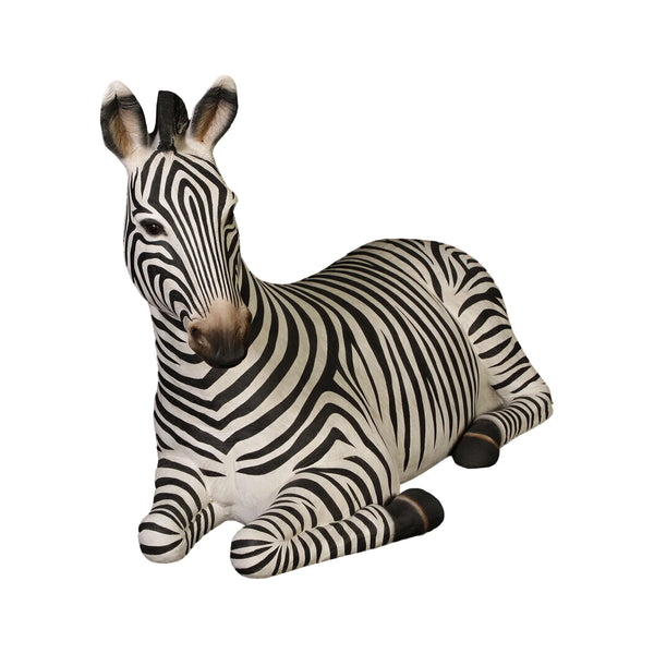 Decorative statue of a resting zebra featuring black and white stripes and tucked legs.