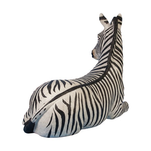 Decorative statue of a resting zebra featuring black and white stripes and tucked legs.
