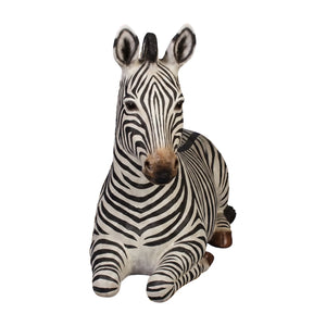 Decorative statue of a resting zebra featuring black and white stripes and tucked legs.