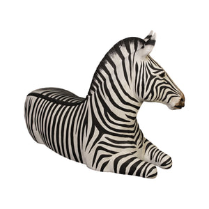 Decorative statue of a resting zebra featuring black and white stripes and tucked legs.