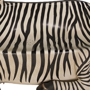 Decorative chair designed to look like a resting zebra with black and white stripes and an integrated seat.