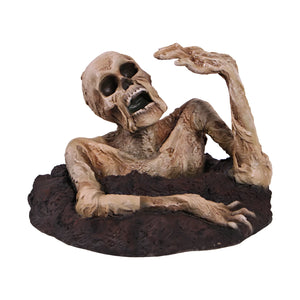 Decorative skeleton statue with mummified skin details and an open mouth, appearing to crawl out of a textured dirt base.