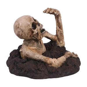 Decorative skeleton statue with mummified skin details and an open mouth, appearing to crawl out of a textured dirt base.