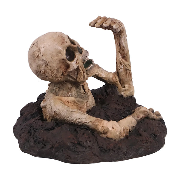 Decorative skeleton statue with mummified skin details and an open mouth, appearing to crawl out of a textured dirt base.