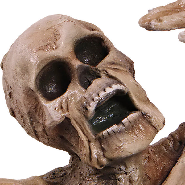 Decorative skeleton statue with mummified skin details and an open mouth, appearing to crawl out of a textured dirt base.