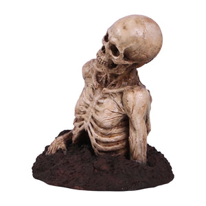 Decorative skeleton statue featuring mummified skin details and a tilted skull, emerging from a textured dirt base.